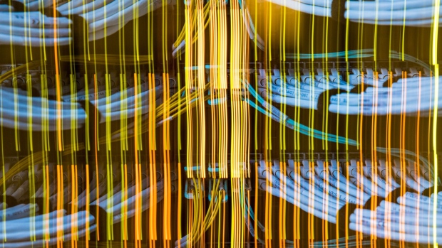 Light trails from network switches illuminate fiber optic cables, center, and copper Ethernet cables inside a communications room at an office in London, U.K., on Monday, May 21, 2018. The Department of Culture, Media and Sport will work with the Home Office to publish a white paper later this year setting out legislation, according to a statement, which will also seek to force tech giants to reveal how they target abusive and illegal online material posted by users. Photographer: Jason Alden/Bloomberg