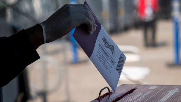 A resident wearing a protective glove drops a ballot into a ballot box at an early voting polling location for the 2020 Presidential election in San Francisco, California, U.S., on Tuesday, Oct. 6, 2020. In June, Governor Newsom signed a one-time-only bill making the November election a mail-ballot vote in hopes of protecting voters from the coronavirus. Photographer: David Paul Morris/Bloomberg