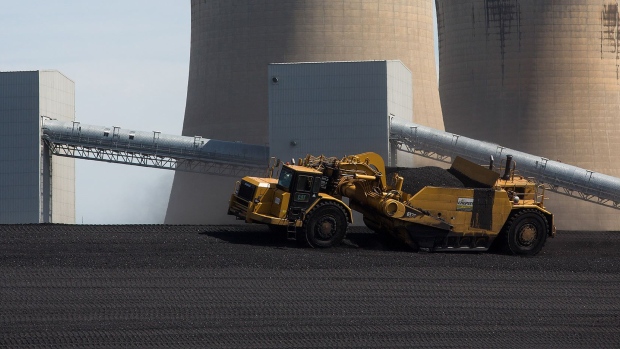 Vehicles move coal ash as cooling towers stand in the Drax Group Plc's power station near Selby, U.K., on Wednesday, May 4, 2016. Drax Group Plc, the utility converting the U.K.'s biggest coal station to a plant generating heat from compressed waste, says its commitment to curbing pollution could result in getting government support. Photographer: Simon Dawson/Bloomberg
