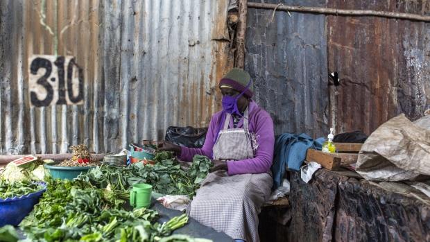 A vendor wearing a protective face mask cuts herbs and leaves for sale on her vegetable stall at Toi market in Nairobi, Kenya, on Tuesday, May 26, 2020. Kenya plans to spend 53.7 billion shillings ($503 million) on a stimulus package to support businesses that have been hit by the coronavirus pandemic, according to the National Treasury.