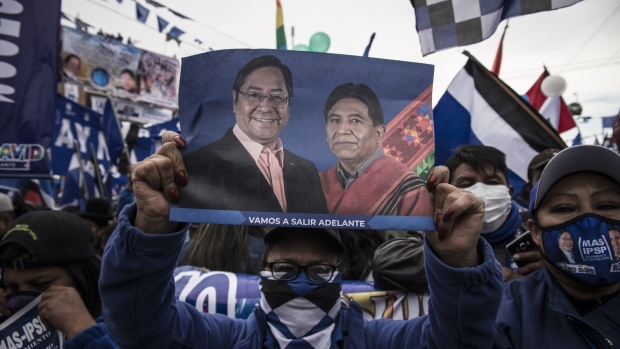 An attendee holds a sign displaying the images of Luis Arce, presidential candidate for the Movement for Socialism party (MAS), and David Choquehuanca, vice presidential candidate for the Movement for Socialism party (MAS), during a campaign rally in La Paz, Bolivia, on Wednesday, Oct. 14, 2020. Former Economy and Public Finance Minister Luis Arce leads voter intention with 33.6% to 26.8% for former President Carlos Mesa. Photographer: Marcelo Perez del Carpio/Bloomberg