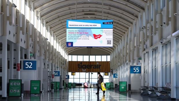 A screen displays New South Wales Covid-19 safety protocols for people that have 'been in Victoria in the last 14 days' at a deserted Sydney Airport in Sydney, Australia, on Friday, Aug. 17, 2020. Sydney Airport plans to raise A$2 billion ($1.4 billion) selling shares to help weather the coronavirus crisis as travel restrictions slam the aviation industry. Photographer: Brendon Thorne/Bloomberg