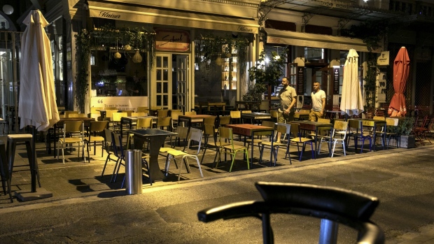 Pedestrians walk outside closed bars in Athens, Greece, on Wednesday, Aug. 19, 2020. After posting last week its highest daily increase since the start of the pandemic, Greece on Monday introduced new restrictions, requiring bars and restaurants to close between midnight and 7 a.m. in the greater Athens region.
