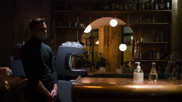 A bottle of hand sanitizer and a waiter sit at the vacant bar in Restaurant Les Carrieres as new Covid-19 restrictions come into force, closing bars and restaurants early, in Paris, France, on Monday, Sept. 28, 2020. President Emmanuel Macron’s government is seeking to ease tension after the first significant tightening of restrictions on French daily life since the end of the lockdown in May. Photographer: Nathan Laine/Bloomberg