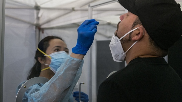 A medical worker wearing personal protective equipment (PPE) administers a rapid Covid-19 test to a traveler at San Francisco International Airport (SFO) in San Francisco, California, U.S., on Thursday, Oct. 15, 2020. 