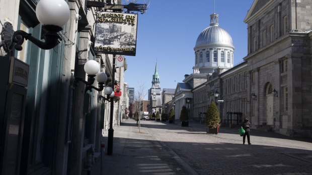 A pedestrian walks near the Bonsecours Market in the Old Montreal neighborhood of Montreal, Quebec, Canada, on Friday, March 27, 2020. Quebec Premier Francois Legault said he’s putting Quebec “on pause” to limit the coronavirus outbreak and stem physical contact.