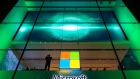 A customer stands near the Microsoft Corp. logo during the Microsoft Corp. Xbox One X game console global launch event in New York, U.S., on Monday, Nov. 6, 2017. As Microsoft Corp. begins selling a new Xbox console, the focus of its video-game unit is shifting toward software and services. The company plans to increase investment in developing in-house video games. 