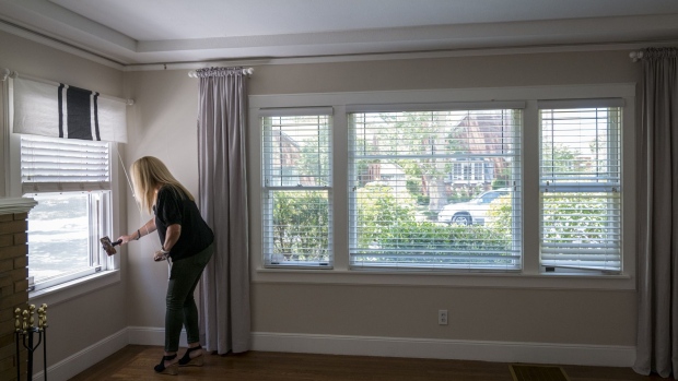 A realtor wearing a protective mask uses a smartphone to provide a virtual video tour of a home for sale in Sacramento, California, U.S., on Monday, June 29, 2020. Contract signings to purchase previously owned U.S. homes surged in May by the most on record as mortgage rates fell and some states began to reopen from coronavirus lockdowns.