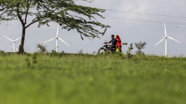 A motorcyclist and passenger ride near wind turbines manufactured by Inox Wind Ltd. operating near electricity cables at the Ostro Energy Pvt. Lahori Wind Farm in Lahori, Madhya Pradesh, India, on Monday, Aug. 14, 2017. As of June, India had 32 gigawatts of wind capacity. The nation is aiming to raise that to 60 gigawatts by 2022 as part of the country's climate pledge. Photographer: Dhiraj Singh/Bloomberg