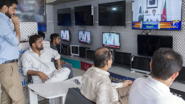 People watch screens showing a speech by Imran Khan, chairman of Pakistan Tehreek-e-Insaf (PTI), also known as Movement for Justice, at a store in Karachi, Pakistan, on Thursday, July 26, 2018. Former cricket star Khan declared victory in Pakistan’s election, boosting stocks as investors bet he’d be able to form a stable government that could address the nation’s financial woes after a vote tarred by rigging allegations. Photographer: Asim Hafeez/Bloomberg