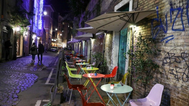 Pedestrians walk past empty restaurant tables along a cobbled street in Rome, Italy, on Thursday, Oct. 22, 2020. Italy reported record new coronavirus infections on Wednesday as Rome and Milan, the country's political and financial capitals, prepare for a night-time curfew. Photographer: Alessia Pierdomenico/Bloomberg