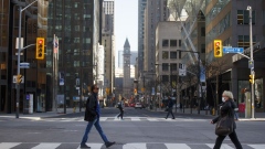 Morning commuters cross Yonge Street at Bay Street in the financial district of Toronto, Ontario, Canada, on Friday, May 22, 2020. 