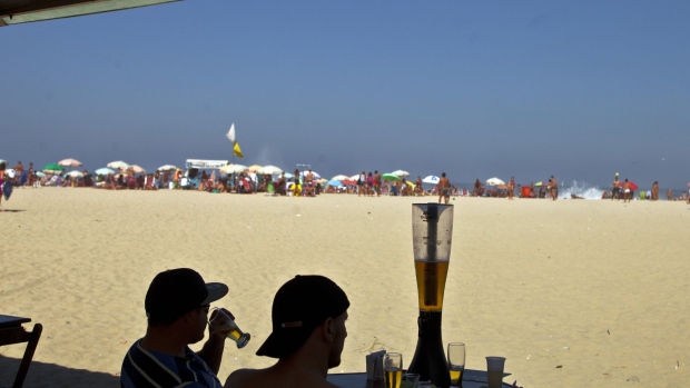 Two men drink beer at the Copacabana beach in Rio de Janeiro, Brazil, on Saturday, Aug. 4, 2013. Investors are betting on billionaire Jorge Paulo Lemann to help bolster profit at Cia. de Bebidas das America this year as Brazilians buy less beer. Photographer: Dado Galdieri/Bloomberg