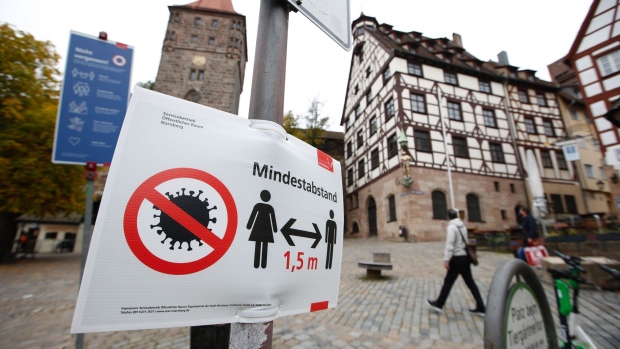 Pedestrians pass a social distancing sign in Nuremberg, Germany, on Monday, Oct. 19, 2020. Chancellor Angela Merkel’s top health official ruled out a second nationwide lockdown even as he warned Germany risks losing control over a resurgent pandemic with a record number of new cases.