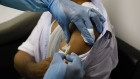 A health worker injects a person during clinical trials for a COVID-19 vaccine