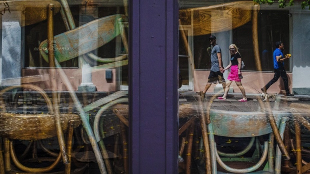 Pedestrians are reflected in the windows of a closed restaurant in the South Beach neighborhood of Miami Beach, Florida, U.S., on Friday, March 20.