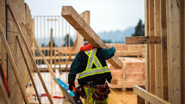 A worker carries a support beam through the Adera Development Corp. Duet mass-timber construction site in Coquitlam, British Columbia, Canada, on Tuesday, Feb. 11, 2020. Across Canada, there are plans to build more wood highrises, as the federal building code is set to allow wooden buildings of up to 12 stories, when it's revised later this year, CBC reports. Photographer: James MacDonald/Bloomberg