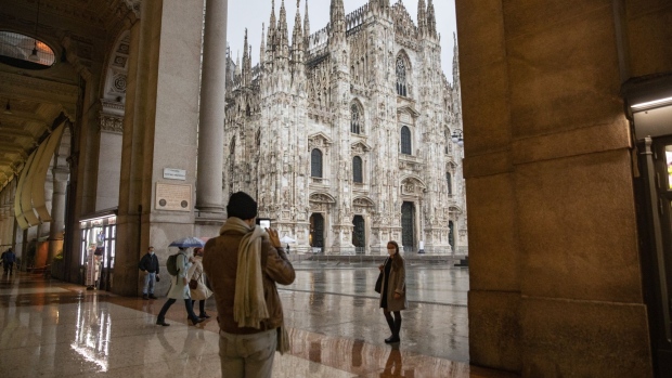 A visitor takes a photograph of a person standing in front of the Duomo Cathedral in Milan, Italy, on Monday, Oct. 26, 2020. Italy introduced its strongest virus restrictions since the end of a lockdown in May, and Spain will impose new measures, including a nationwide curfew. Photographer: Francesca Volpi/Bloomberg