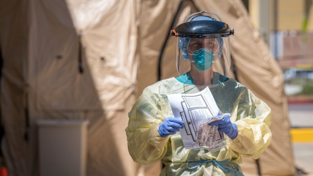 A medical personnel wearing personal protective equipment (PPE) walks towards a car at a COVID-19 drive-thru testing site in San Pablo, California, U.S., on Tuesday, April 28, 2020. California, which has closed schools for the academic year, is considering bumping up the start of the new school year to late July or early August, Governor Gavin Newsom said. Photographer: Bloomberg/Bloomberg