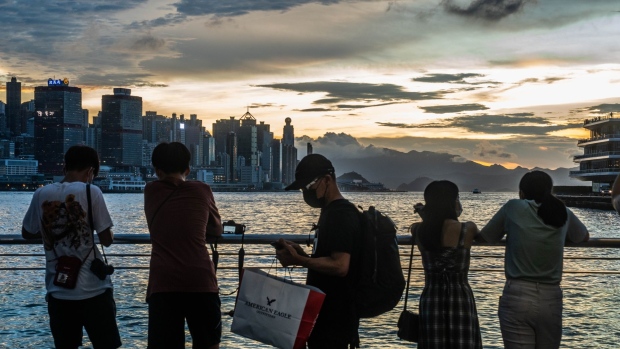 People wearing protective face masks watch the sunset outside Harbour City in Hong Kong, China, on Friday, Sept. 11, 2020. Hong Kong doubled the number of people allowed to gather in public and reopened sports venues beginning Friday, in the latest easing of restrictions as coronavirus cases drop from record highs. Photographer: Lam Yik/Bloomberg