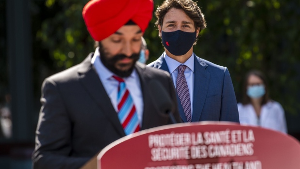 Justin Trudeau, Canada's prime minister, right, listens while Navdeep Bains, Canada's innovation, science and industry minister, speaks at the National Research Council of Canada (NRC) Royalmount Human Health Therapeutics Research Centre facility in Montreal, Quebec, Canada, on Monday, Aug. 31, 2020. Trudeau said that Canada has agreed to buy more than 100 million Covid-19 vaccines from Novavax Inc. and Johnson & Johnson.