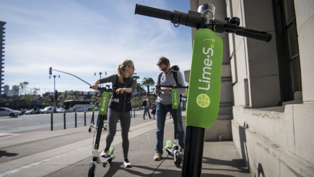 People use a smartphone to unlock Neutron Holdings Inc. LimeBike shared electric scooters on the Embarcadero in San Francisco, California, U.S., on Thursday, May 3, 2018. City officials, eager to do something about the electric scooters issue, are sending cease-and-desist letters and are planning to require permits soon, while impounding any that they say are parked illegally. Photographer: David Paul Morris/Bloomberg