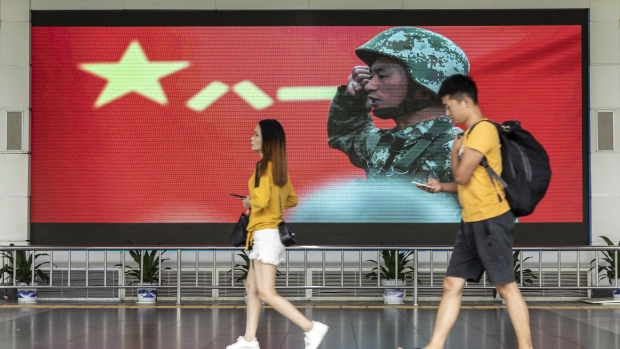 Pedestrians walk past an advertisement for the People's Liberation Army (PLA) on a screen near the Luohu border crossing in Shenzhen, China, on Thursday, Aug. 15, 2019. China plans to let Shenzhen City, which borders Hong Kong, play "a key role" in science and technology innovation in the Guangdong-Hong Kong-Macau Greater Bay Area, according to state media. Photographer: Qilai Shen/Bloomberg