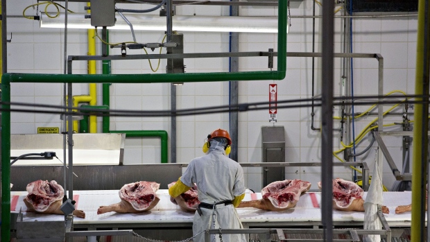 An employee handles sides of pork on a conveyor at a Smithfield Foods Inc. pork processing facility in Milan, Missouri, U.S., on Wednesday, April 12, 2017. WH Group Ltd. acquired Virginia-based Smithfield, the world's largest pork producer, in 2013 for $6.95 billion. As Smithfield can't export sausage, ham and bacon from its U.S. factories, because China prohibits imports of processed meat, WH Group opened an 800 million-yuan ($116 million) factory in Zhengzhou that will produce 30,000 metric tons of those meats when it reaches full capacity next year. Photographer: Daniel Acker/Bloomberg