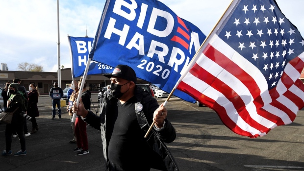 A man carries a Biden-Harris flag and an American flag as supporters of Joe Biden prepare to hold a car parade to celebrate the outcome of Tuesday's election on November 7, 2020 in Las Vegas.