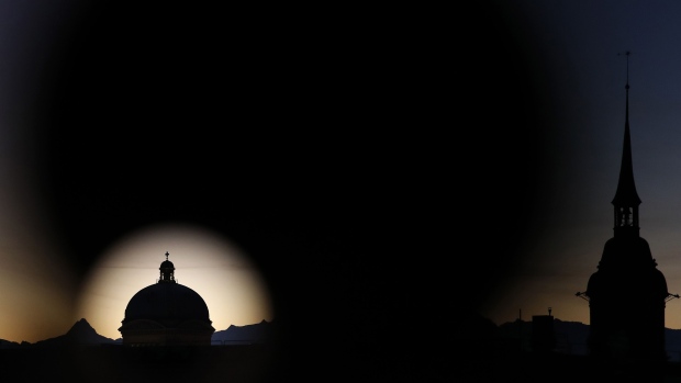 The Federal Palace, Switzerland's parliament building, left, stands silhouetted during sunrise in Bern, Switzerland, on Wednesday, Jan. 16, 2019. With SNB policy rates below zero, investors hungry for returns have piled into local real estate, pushing up prices. Photographer: Stefan Wermuth/Bloomberg