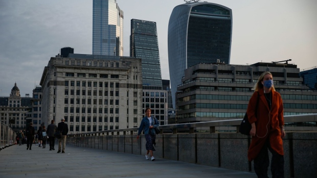 Commuters cross London Bridge in view of skyscrapers in the City of London square mile financial district in London, U.K., on Friday, Sept. 11, 2020. Britain recorded strong economic growth in July as coronavirus restrictions eased, but mounting job losses and the risk of a messy Brexit are threatening a turbulent end to the year.