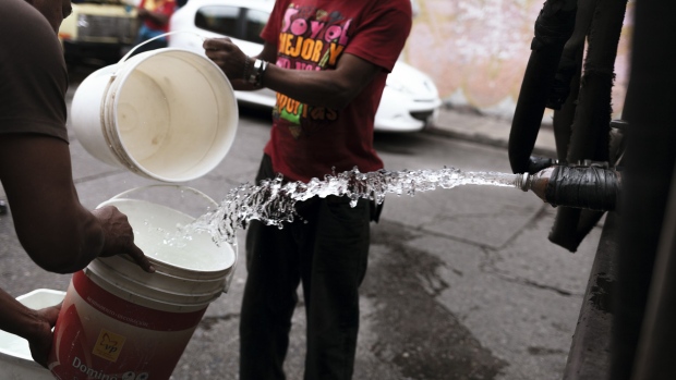 Residents fill buckets during delivery from a water supply truck in Caracas, Venezuela, on Saturday, July 28, 2018. In a country where inflation is forecast to reach 1 million percent, an egalitarian disaster is also taking hold, a man-made drought is leaving residents from all social backgrounds without water. Photographer: Adriana Loureiro Fernandez/Bloomberg