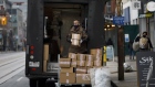 A courier wearing a protective mask picks up boxes from a shop on Queen St. in Toronto, Ontario, Canada, on Monday, Nov. 23, 2020.