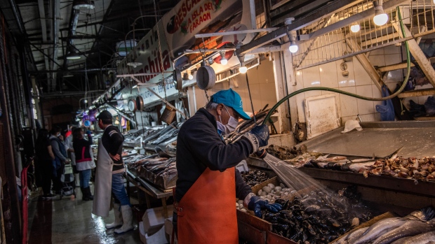 A worker wearing a protective mask washes seafood at a stand inside a fish market in Santiago, Chile, on Friday, April 17, 2020. Chile has confirmed more than 9,700 infections nationwide, as lockdown measures continue. Photographer: Cristobal Olivares/Bloomberg