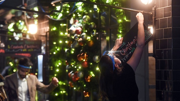 LONDON, ENGLAND - DECEMBER 15: A waiter is seen removing a Christmas themed sign from outside a restaurant, ahead of London being moved into Tier 3 of the pandemic-control system on Wednesday, on December 15, 2020 in London, England. In 'Tier 3' of England's pandemic-control measures, restaurants and pubs will be limited to takeaway and delivery, although shops are allowed to remain open. (Photo by Peter Summers/Getty Images)