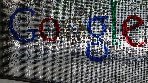 A visitor passes a sign featuring Google Inc.'s logo inside their U.K. headquarters at Six St Pancras Square in London. Photographer: Chris Ratcliffe/Bloomberg