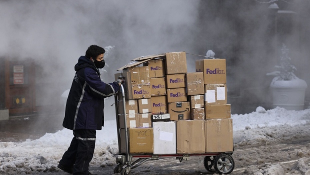 A driver for an independent contractor to FedEx Corp. pushes a cart of packages through snow in New York, U.S., on Thursday, Dec. 17, 2020. Winter Storm Gail pounded the city as temperatures dropped to 27 degrees with frigid sustained winds up to 35 mph, making dining outdoors unbearable amid the Covid-19 pandemic that has already crippled the restaurant industry. Photographer: Angus Mordant/Bloomberg