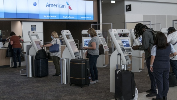 Travelers wearing protective masks use check-in kiosks at an American Airlines Group counter.