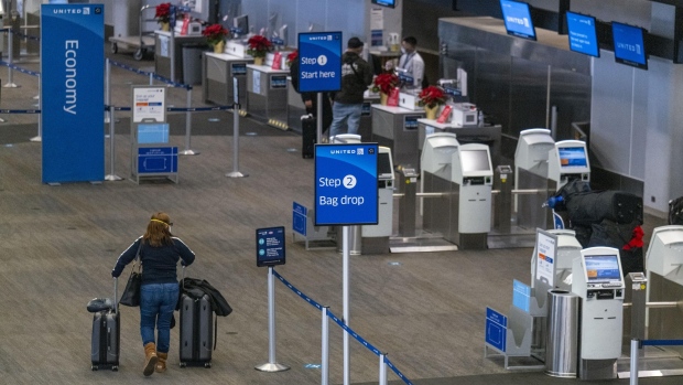A traveler wearing a protective mask walks with luggage to the United Airlines Holdings Inc. check-in counter at San Francisco International Airport (SFO) in San Francisco, California, U.S., on Monday, Dec. 21, 2020. Airline passenger numbers in the U.S. totaled 1.06 million on Dec. 20, compared with 2.52 million the same weekday a year earlier, according to the Transportation Security Administration.