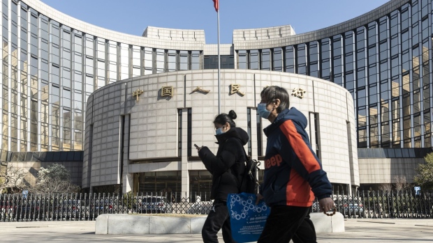 Pedestrians wearing protective masks walk past the People's Bank of China (PBOC) building in Beijing, China, on Tuesday, March 17, 2020. China suffered an even deeper slump than analysts feared at the start of the year as the coronavirus shuttered factories, shops and restaurants across the nation, underscoring the fallout now facing the global economy as the virus spreads around the world. Photographer: Qilai Shen/Bloomberg