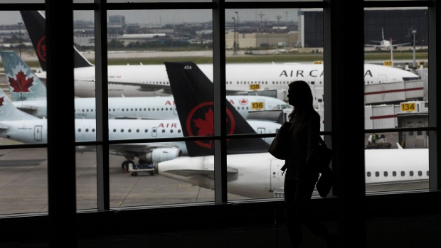 A traveler walks past Air Canada planes at Toronto Pearson International Airport (YYZ) in Toronto.
