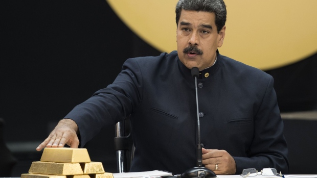 Nicolas Maduro, Venezuela's president touch a pile of 12 Kilogram gold ingots during a press conference on 'Petro' cryptocurrency in Caracas, Venezuela, on Thursday, March 22, 2018. U.S. President Trump banned U.S. purchases of 'Petro' cryptocurrency as part of a campaign to pressure the government of President Nicolas Maduro.