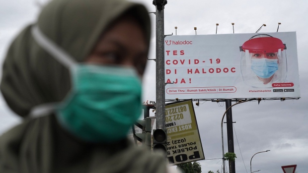 A pedestrian wearing a protective face mask walks past an advertisement for coronavirus tests in Bandung, West Java, Indonesia on Thursday, Dec. 10, 2020. The first batch of Covid-19 vaccine ordered from Chinas Sinovac Biotech Ltd. has arrived in Jakarta Sunday and transported to Indonesias state-owned company PT Bio Farma in Bandung.