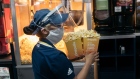A worker wearing carries buckets of popcorn at the concessions counter inside a Cinepolis movie theater in Mexico City.