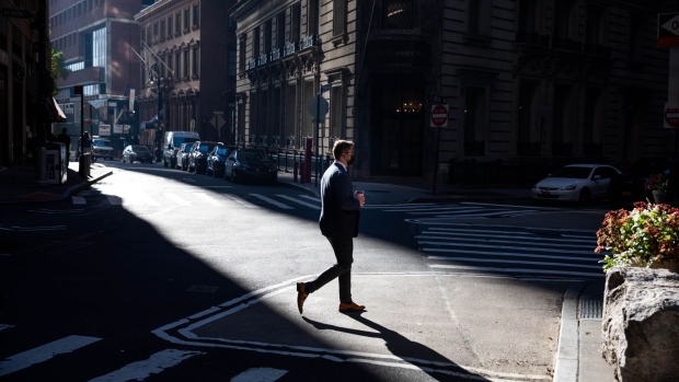 A pedestrian wearing a protective mask crosses Williams Street near the New York Stock Exchange (NYSE) in New York, U.S., on Monday, Nov. 9, 2020. Stocks surged around the world and bonds tumbled after a large-scale coronavirus vaccine study delivered the most-promising results in the battle against the worst pandemic in a century. Photographer: Michael Nagle/Bloomberg