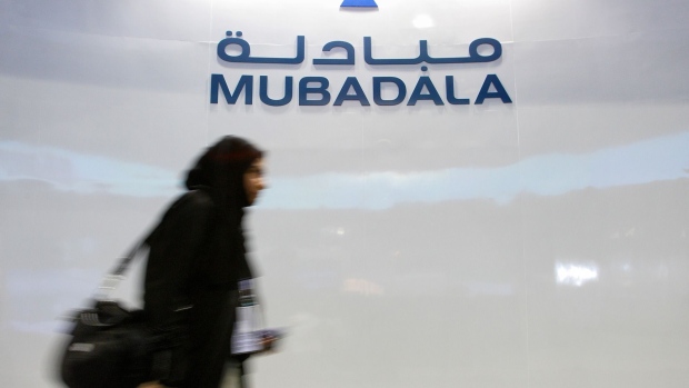 A Mubadala Development Co. employee walks past the company's logo at their exhibition booth during the Singapore Airshow in Singapore . Photographer: JONATHAN DRAKE