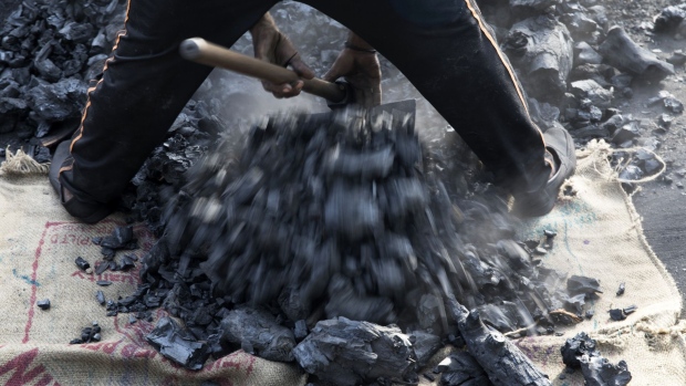 A workers shovels coal at a wholesale supplier's in New Delhi. Photographer: Prashanth Vishwanathan/Bloomberg