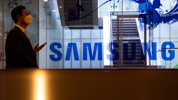 A man wearing a protective mask walks past the Samsung Electronics Co. signage at the company's D'light flagship store in Seoul, South Korea, on Tuesday, Oct. 6, 2020. Samsung were among a list of global firms that were cleared by India’s Ministry of Electronics and Information Technology that won approval to manufacture products in India under a plan aimed at attracting investment of more than 10.5 trillion rupees ($143 billion) for mobile-phone production over the next five years. Photographer: SeongJoon Cho/Bloomberg