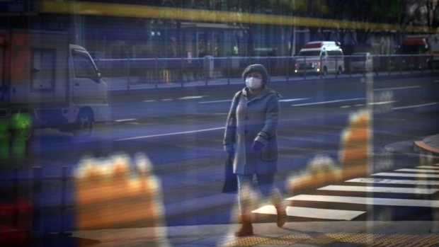 A pedestrian wearing a protective mask is reflected in an electronic stock board outside a securities firm in Tokyo, Japan, on Monday, Jan. 4, 2021.