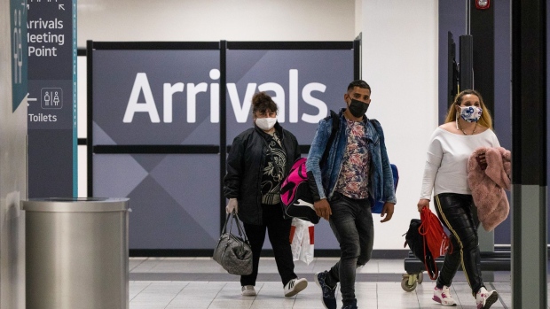 Travelers, wearing a protective face masks, pass through the arrivals area after landing at London Luton Airport in Luton, U.K., on Friday, May 1, 2020. Ryanair Holdings Plc will cut 3,000 jobs and said it will challenge some 30 billion euros ($33 billion) in state aid being doled out to save its European competitors.